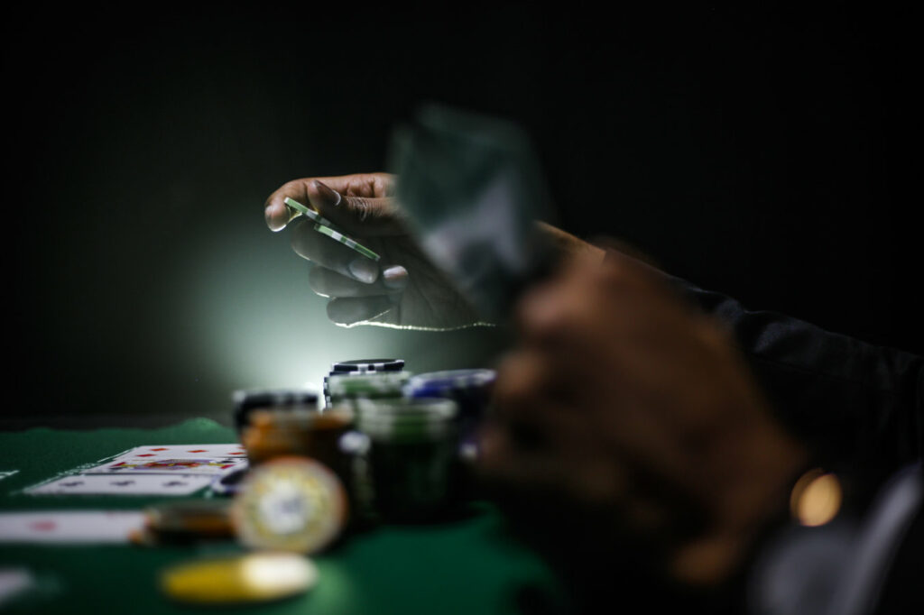 An image of hands holding cards over a table with gambling chips